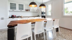 Een moderne keuken met witte kasten, een houten eiland en witte stoelen.