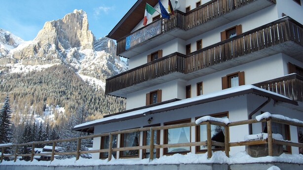 Un hotel de varios pisos con balcones, un paisaje de montañas y banderas.