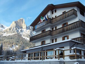 Un hotel de varios pisos con balcones, un paisaje de montañas y banderas.