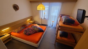 Habitación de hotel con cama, televisor, mesita de noche y ventana con cortinas.