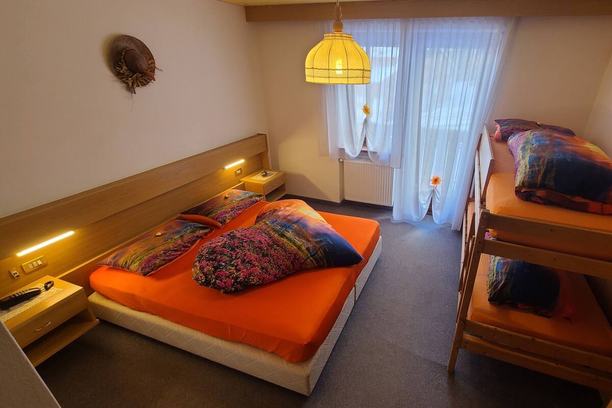 A hotel room with a bed, a TV, a nightstand, and a window with curtains.