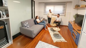 Un salon moderne avec un canapé gris, une table basse et un meuble pour la télévision.