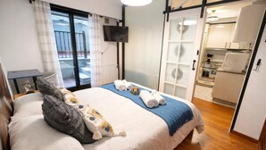 A hotel room with a bed, a TV, a bathroom, and a kitchenette.