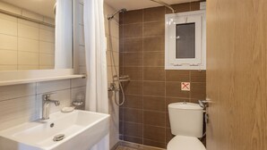 Een badkamer met een wit wastafel, douche en toilet.