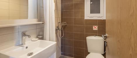 Et badeværelse med en hvid vask, bruser og toilet.