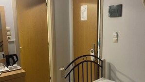Een slaapkamer met een bed, een dressoir, een koffiezetapparaat en een deur.