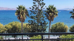 Een balkon met uitzicht op zee, palmbomen en een tafel met een schaal.