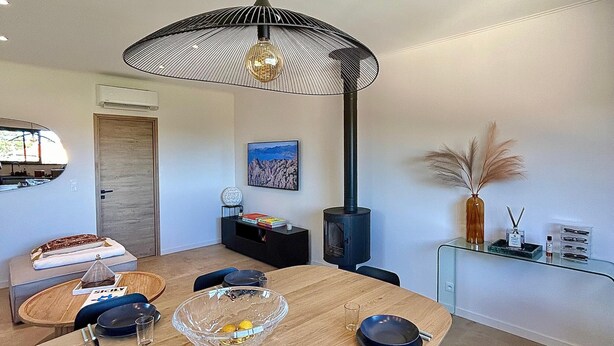Un comedor moderno con una mesa de madera, sillas negras y una lámpara colgante negra y blanca de diseño.