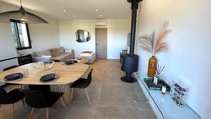 Una sala de estar moderna con comedor, un espejo grande, una chimenea y una mesa de vidrio con sillas.