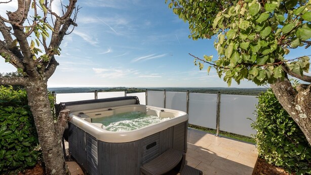 Un bain à remous sur une terrasse extérieure, avec vue sur un lac et des montagnes au loin.