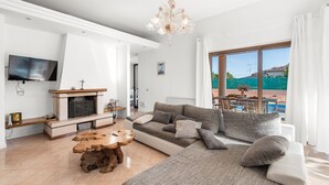 Un salon moderne avec une cheminée, un grand canapé, une table basse et un téléviseur.