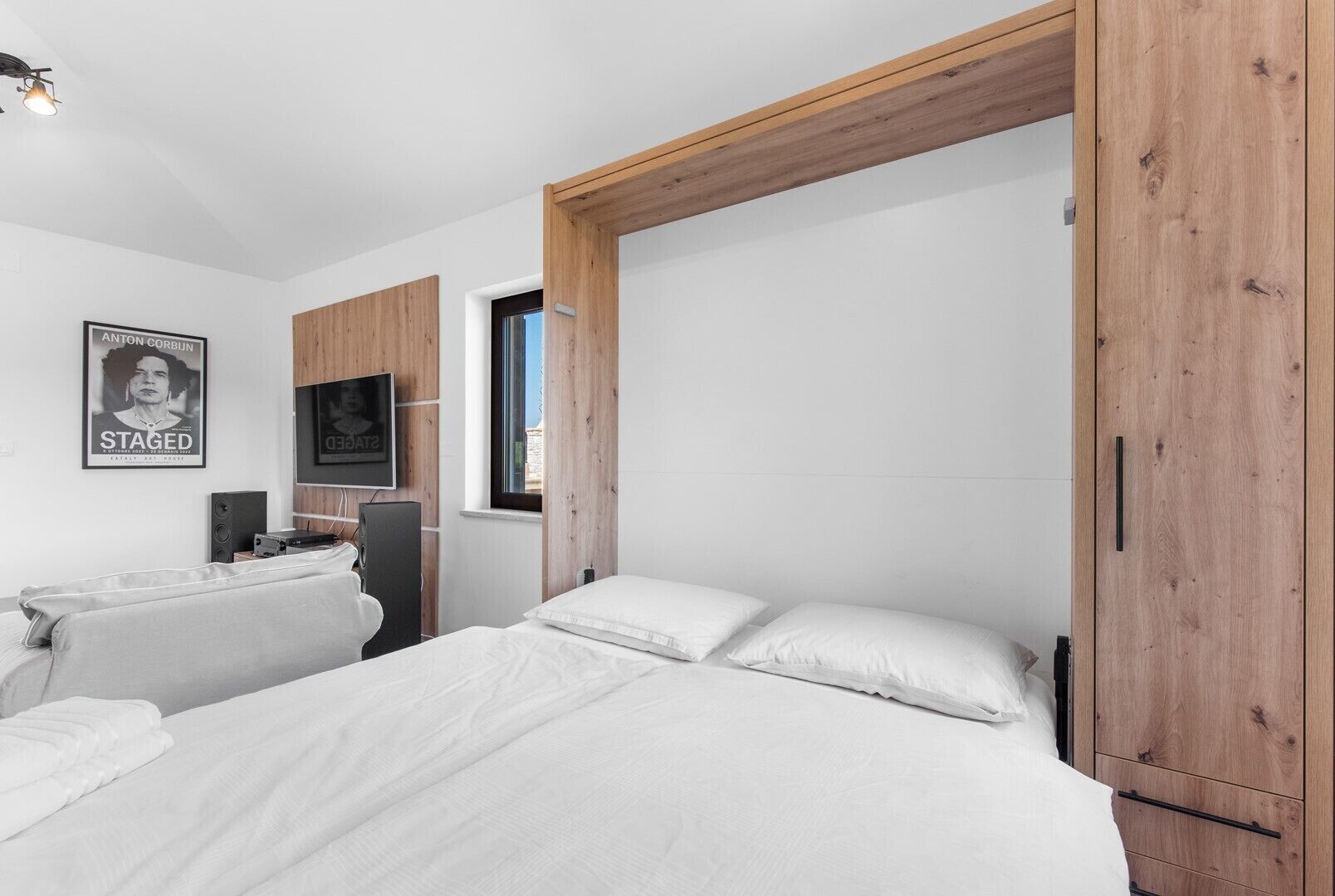 A bedroom with two beds, a TV, a poster, and wooden paneling.