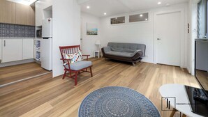 Un salon moderne avec un canapé gris, un fauteuil rouge, une petite table et un tapis à motifs.