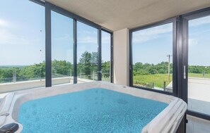 Relax in a serene setting with a large hot tub and expansive views of the lush landscape.
