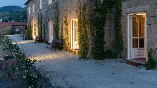 A stone building with ivy-covered walls, a gravel courtyard, and benches.