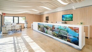A modern reception area with a long reception desk, a mounted television, and a large aquarium display. - Camping Castell Montgrí (Torroella de Montgrí)