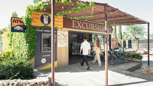 An outdoor building with an ATM and a sign for 'Excursions'. - Camping Castell Montgrí (Torroella de Montgrí)