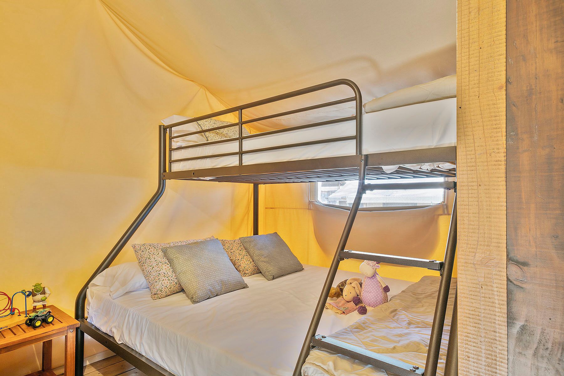 Un lit superposé avec une structure en bois, une literie blanche et des oreillers à motifs.