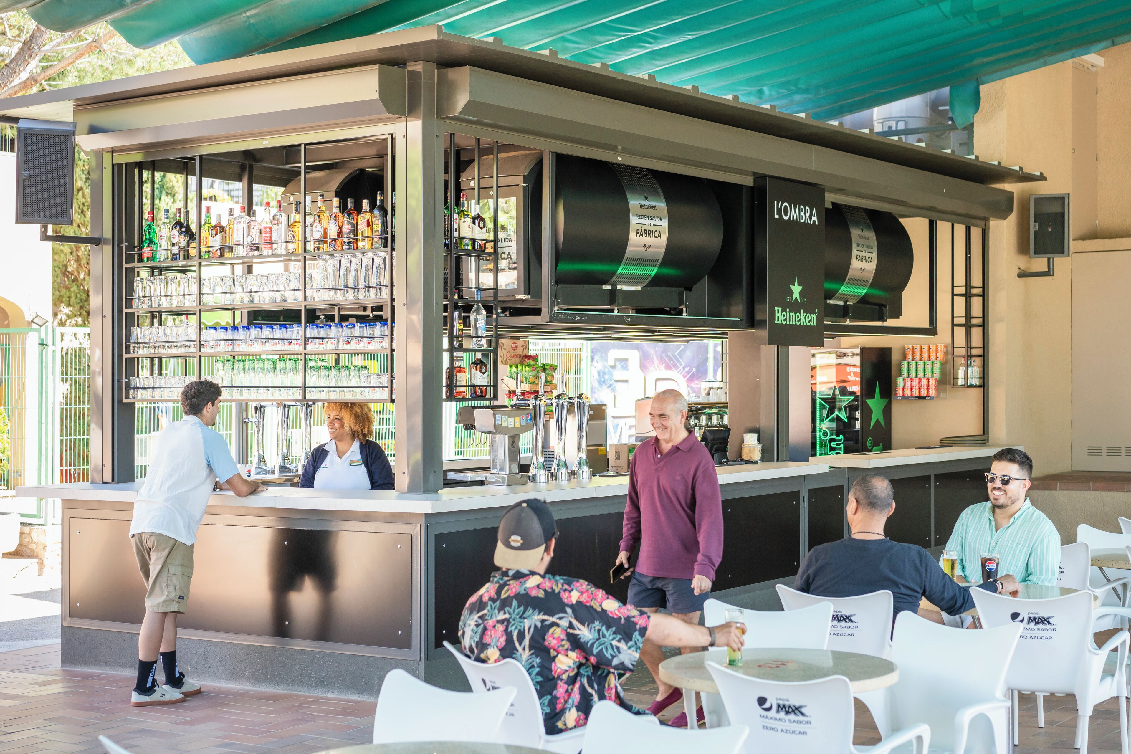 Zona de bar al aire libre con asientos y una barra.