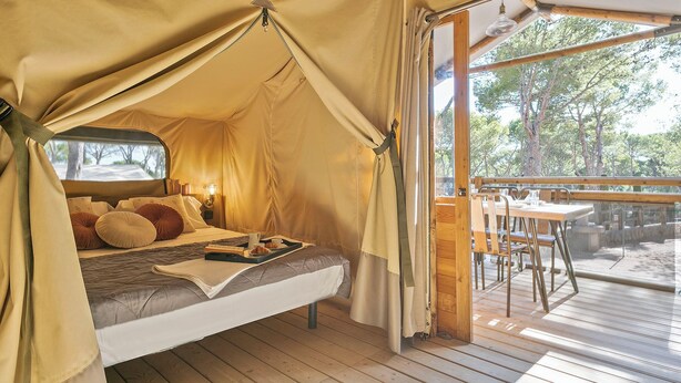 A tented accommodation with a bed, a tray with breakfast items, and a view of the outdoors. - Camping Castell Montgrí (Torroella de Montgrí)