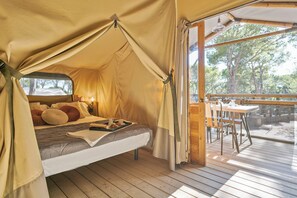 A tented accommodation with a bed, a tray with breakfast items, and a view of the outdoors. - Camping Castell Montgrí (Torroella de Montgrí)