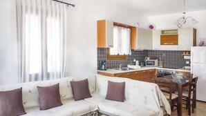 A modern kitchen with a dining area, a sofa with cushions, and a coffee table. - Villa Elena Glysteri (Skopelos)