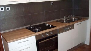 Una cocina moderna con armarios blancos, una hornilla negra y un lavamanos de acero inoxidable.