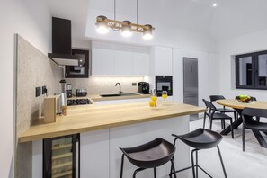 Enjoy cooking in this kitchen with stove, coffee maker, and refrigerator, complemented by a dining area with a table and chairs.