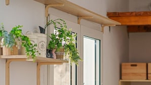 Een keuken met een gasfornuis, een spoelbak en een raam. Boven het raam staan planten in potten.