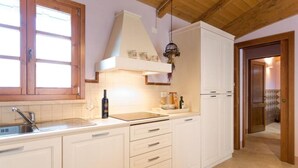 A kitchen with white cabinets, a stainless steel sink, a white countertop, and a wooden ceiling. - Apartment with 2 bedrooms and 2 bathrooms on the ground floor (Toscana)