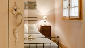 A bedroom with a bed, bedside table, lamp, and a window with curtains. - Apartment with 2 bedrooms and 2 bathrooms on the ground floor (Toscana)