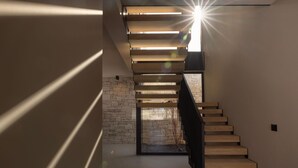 A modern staircase with wooden steps and a stone wall.