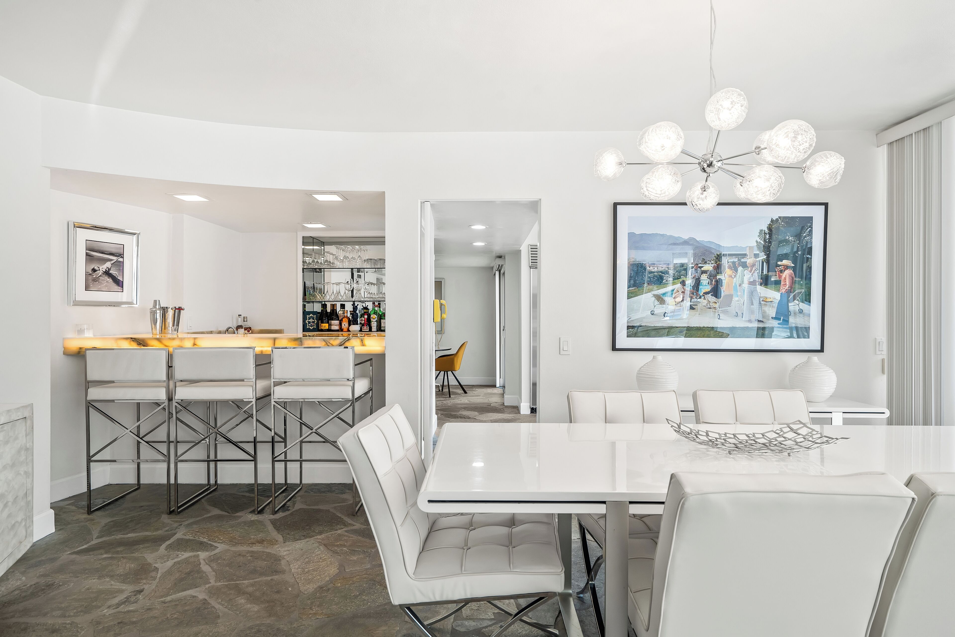 Une cuisine moderne avec un coin bar, des meubles blancs et un grand tableau encadré au mur.