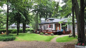 A cabin with a porch, surrounded by trees and a well-maintained lawn. - 500 FT To Beach, Main House, Guest House, Fire Pit (Union Pier)