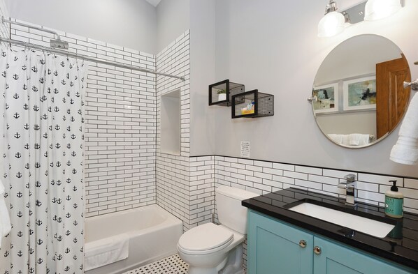 A bathroom with a bathtub, toilet, sink, and a mirror.