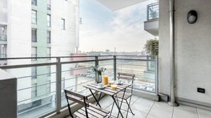 A balcony with a table and chairs, a view of the cityscape, and a building with a modern design. - Bright & Modern 2-Bedroom Apartment in a Quiet Location (Milano)