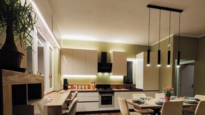 Une cuisine moderne avec un plancher en bois, un coin repas avec des chaises et des luminaires suspendus.