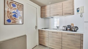 A modern kitchen with wooden cabinets, a sink, and a coffee maker. - Studio Montaigne/ Champs Elysees (Paris)