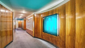 A hallway with wooden paneling, a carpeted floor, and a wall-mounted light fixture. - Studio Montaigne/ Champs Elysees (Paris)