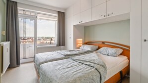 Un dormitorio con dos camas, un ventanal con vistas y una lámpara de techo.