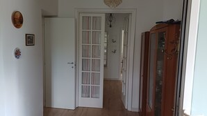 Un corridoio con una porta bianca, un armadietto di legno e un lampadario.