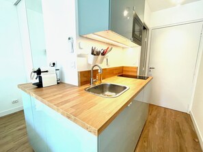 A compact kitchen with a wooden countertop, stainless steel sink, and a microwave above it.