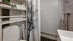 Een badkamer met een douche, toilet en planken met handdoeken.