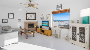 A living room with a sofa, coffee table, TV, fireplace, and a view of the sea. - Apartment With Roof Terrace and Pool - Ref 129 (Mijas)