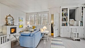 Ein gemütliches Zimmer mit einem blauen Sofa, einem Kamin und einem Bücherregal voller Bücher.