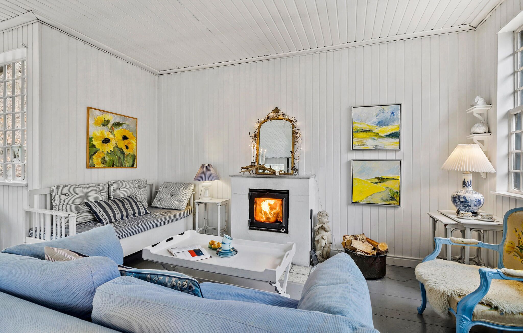 A cozy living room with a fireplace, striped sofas, and artwork on the walls.