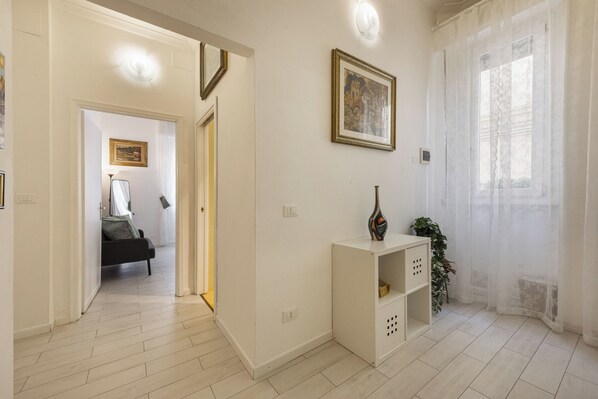 A hallway with a bed, a white console table, a framed picture, and a window with sheer curtains. - Cosimo by MMega (Florence)