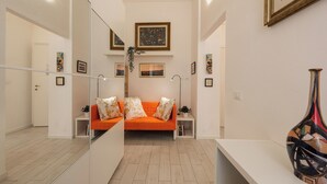 Una sala de estar moderna con un sofá, un espejo y obras de arte enmarcadas en las paredes.