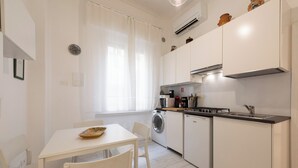 Una cocina moderna con armarios blancos, una mesa de comedor con sillas, una lavadora y un microondas.