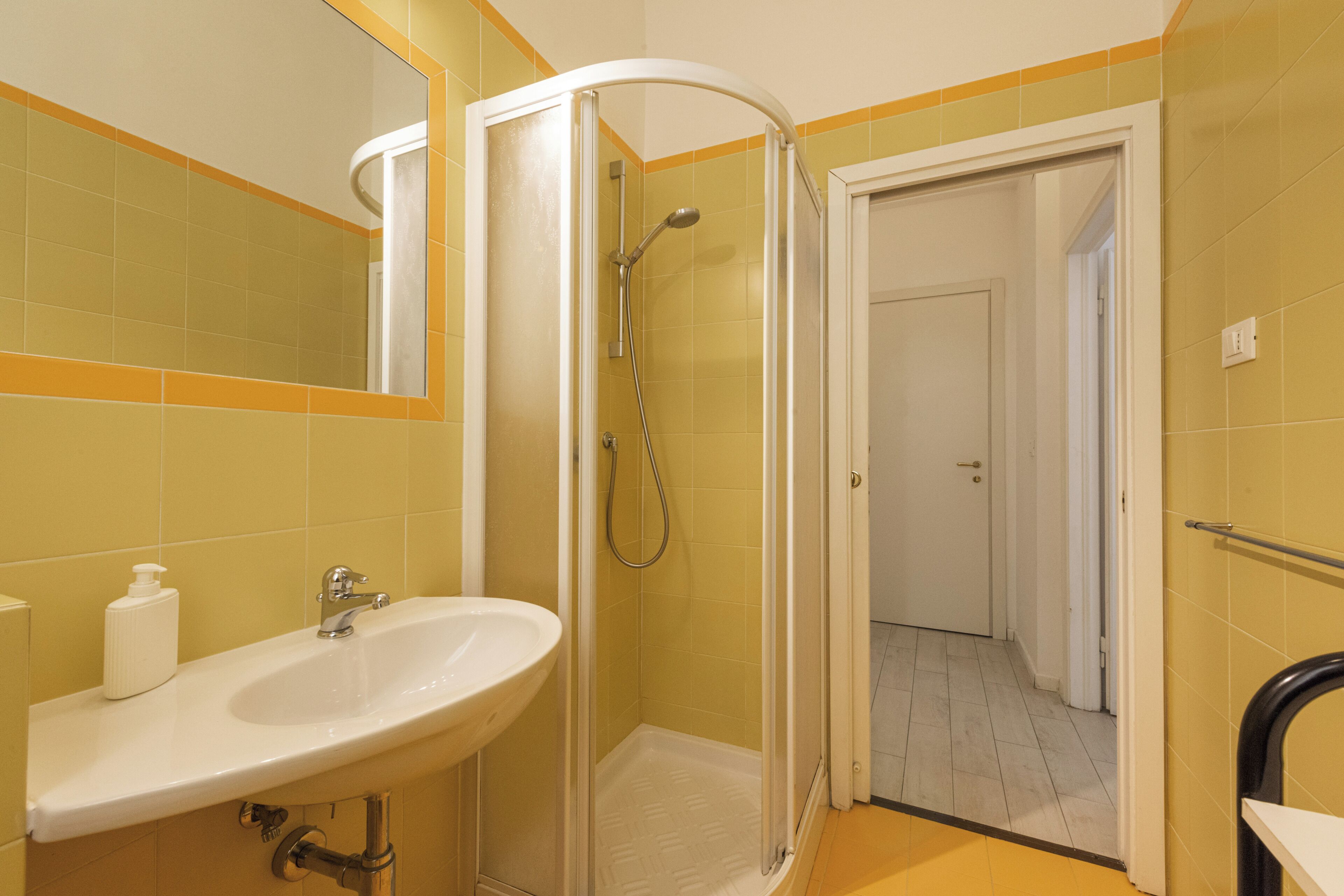 A bathroom with a shower, sink, and mirror.
